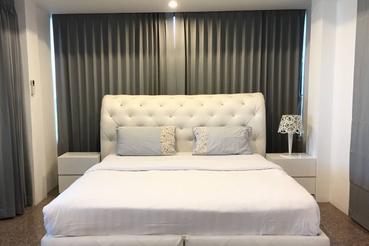 A neatly arranged bedroom with a tufted headboard, two nightstands, and a bed with white bedding.