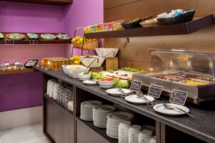 A buffet setup with various food items, including fruits, vegetables, and prepared dishes.