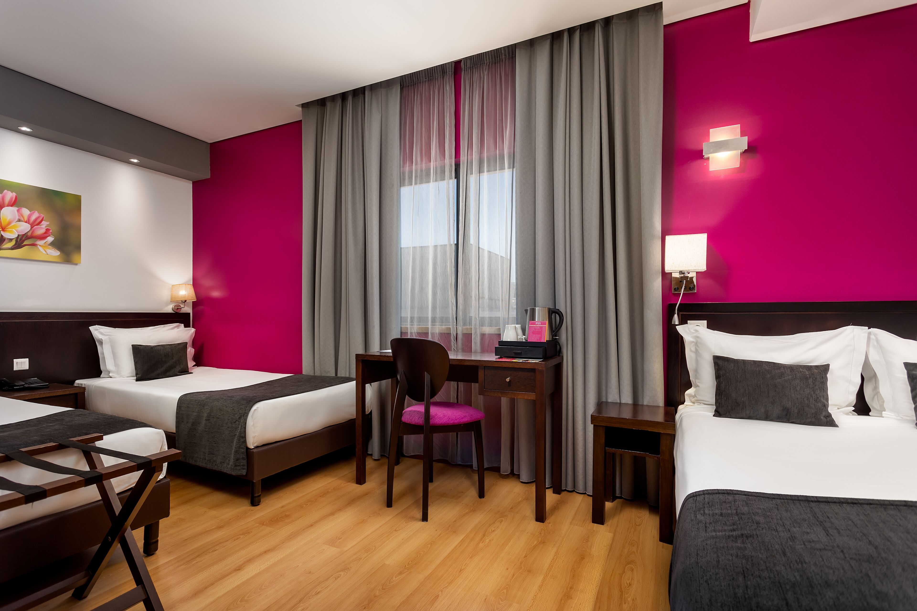 Une chambre d’hôtel avec deux lits, un bureau avec une chaise, une petite table et une table de chevet.