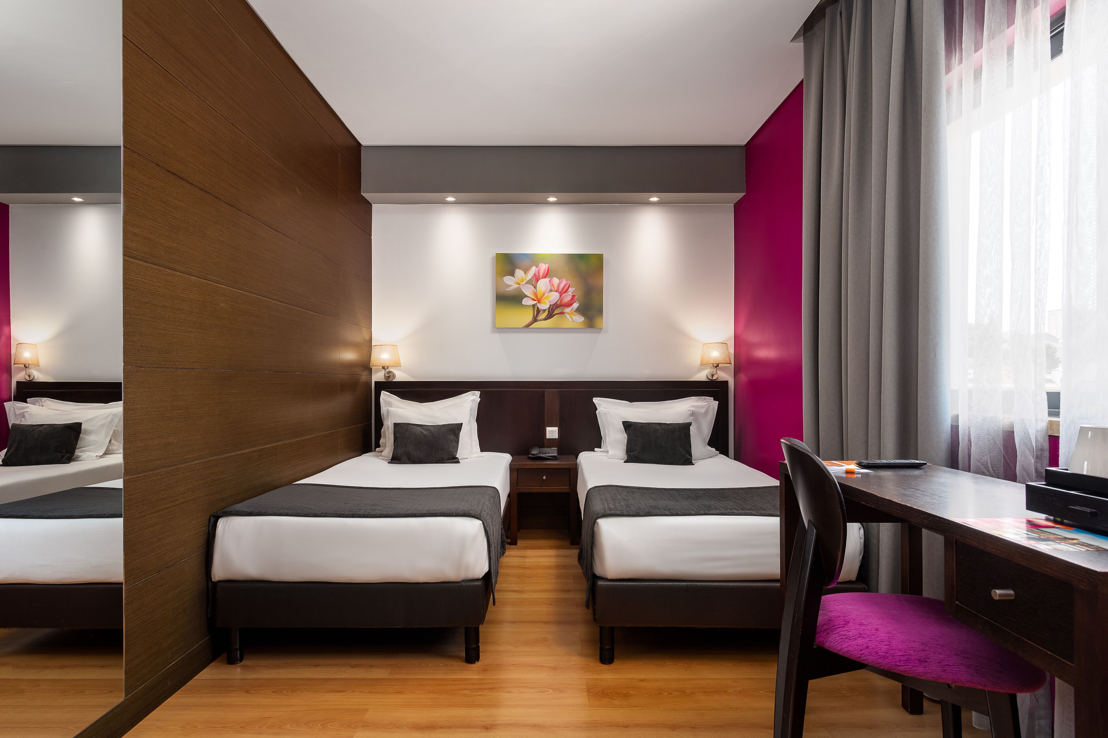 Una habitación de hotel con dos camas, un escritorio, una silla y un cuadro en la pared.