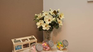 Una mesa con un jarrón de flores blancas, tres frascos de vidrio con tapas y una caja de madera con separadores.