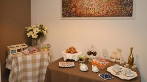 Una mesa con opciones de desayuno, como pasteles, café y té, y un cuadro en la pared.