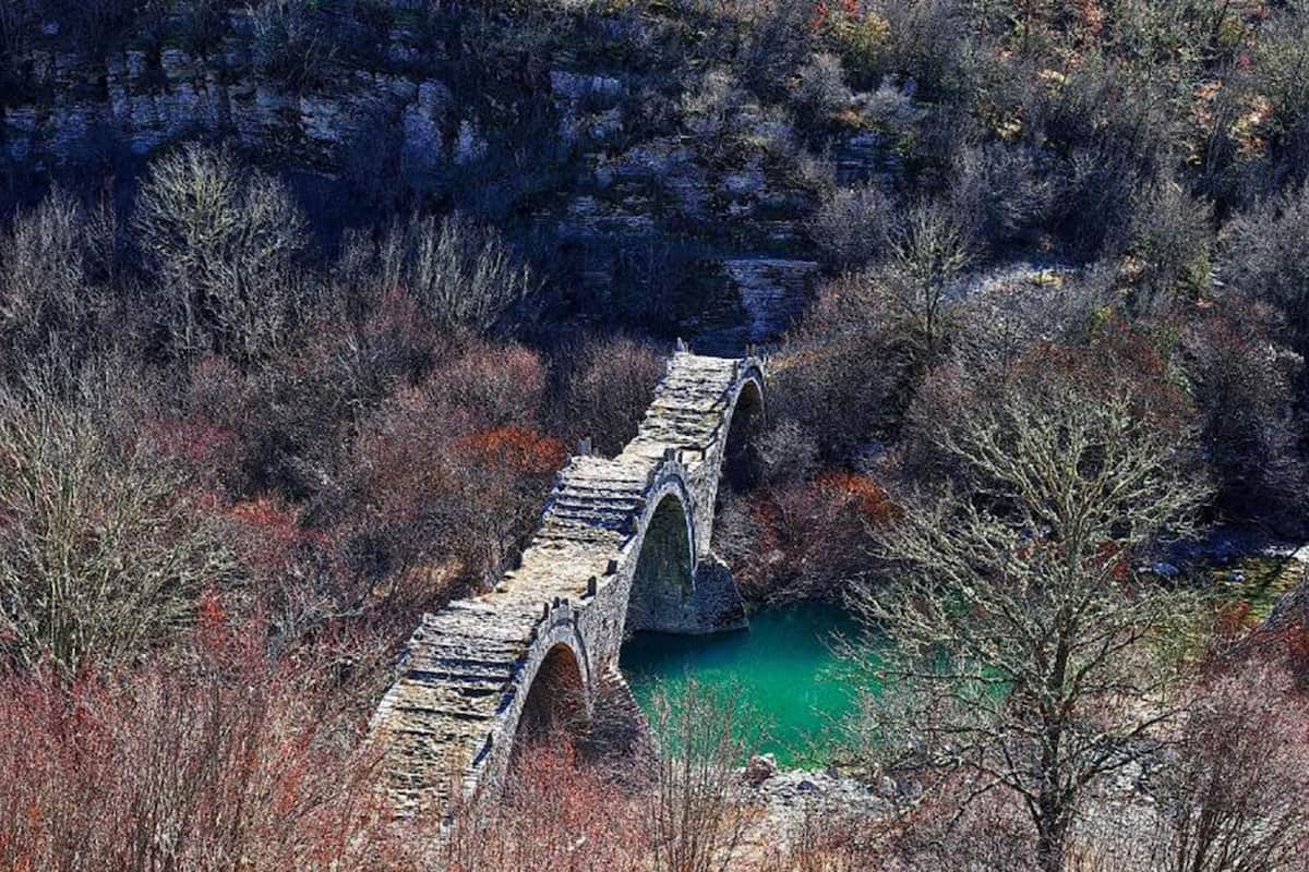A stone bridge over a river surrounded by trees.
