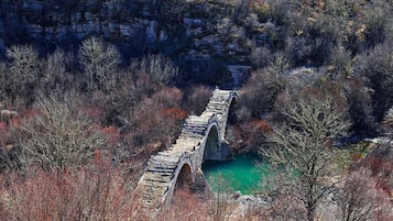 Un pont de pierre enjambant une rivière, le tout entouré d’arbres.