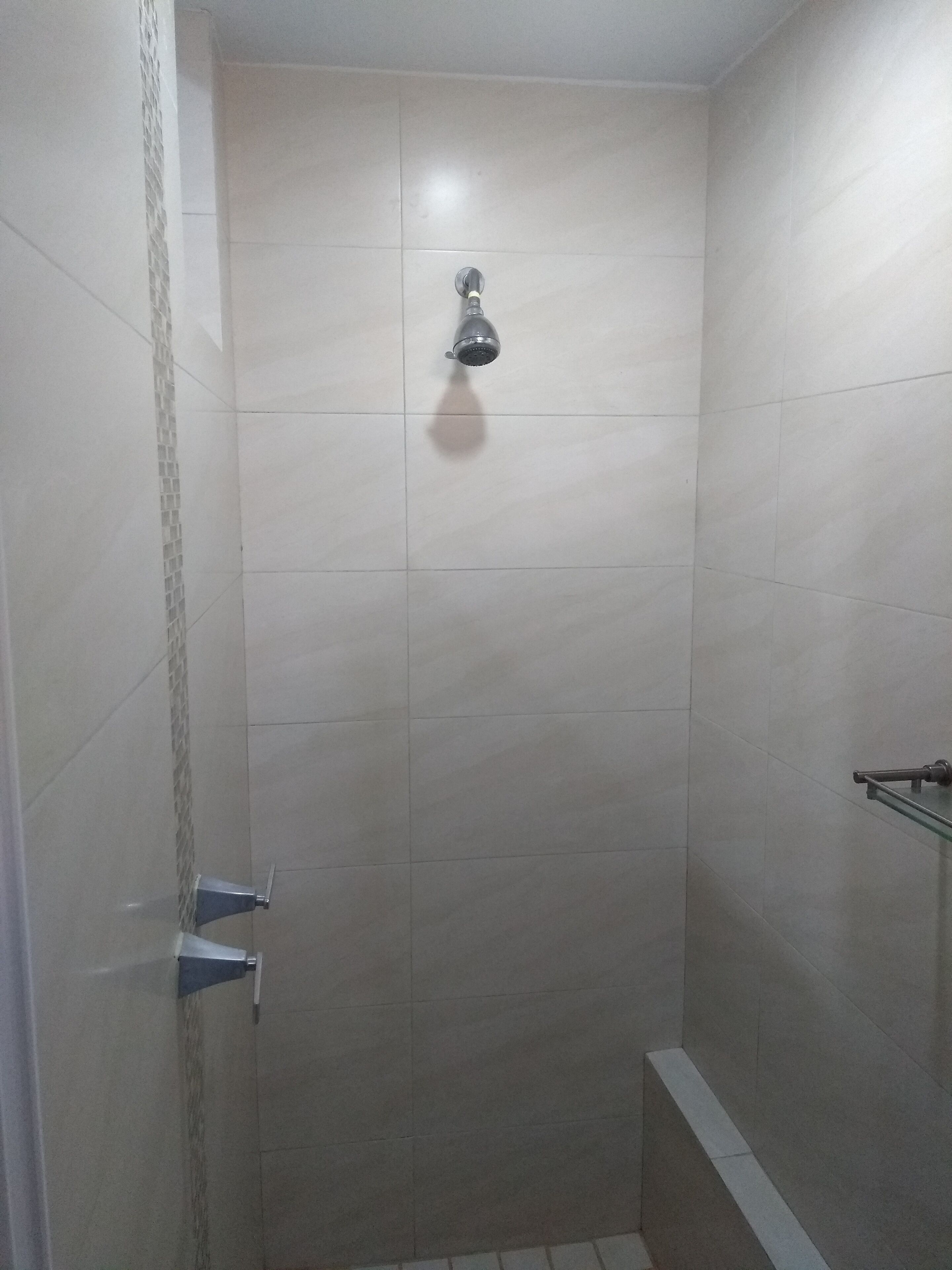 Un espacio de ducha pequeño con azulejos y un cabezal de ducha.