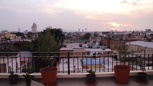A rooftop terrace with potted plants, a basketball court, and a cityscape view. - Suites Chapultepec (Guadalajara)