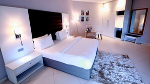 A modern bedroom with a large bed, bedside tables, a chair, a wardrobe, and a mirror. - Fahrenheit Loft (Lagos)