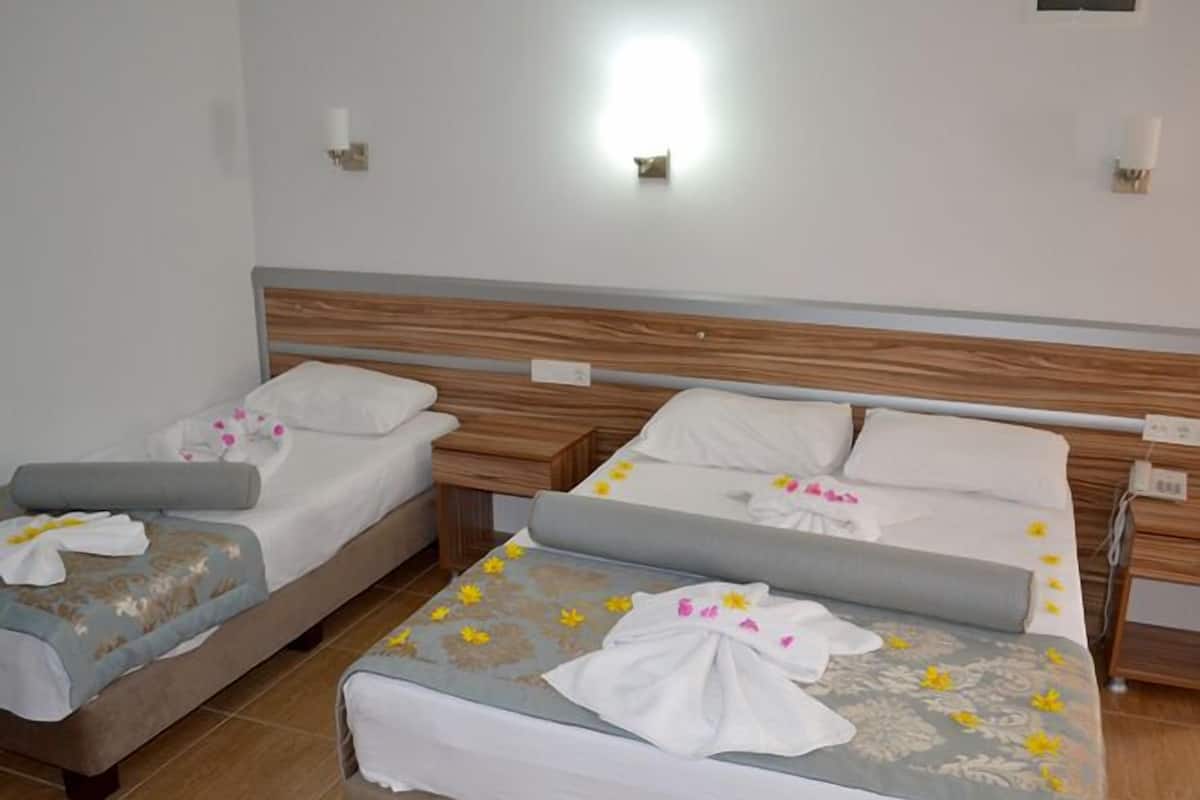 Dos camas individuales con cabeceros de madera, ropa de cama blanca y mantas estampadas con motivos florales.