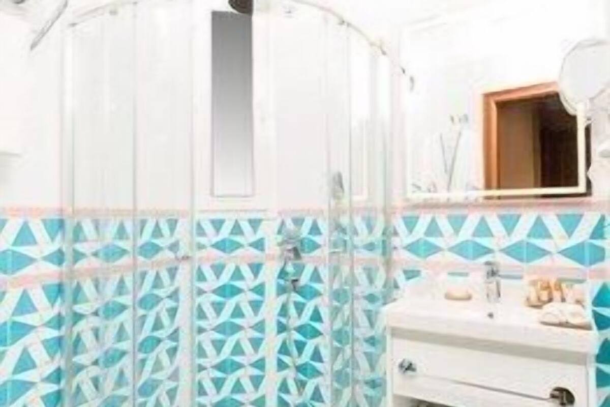 A bathroom with a glass shower enclosure, a white sink, and a mirror above it.
