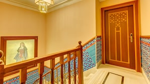 A staircase with a wooden handrail, a framed picture on the wall, a patterned tiled wall, and a wooden door with a geometric design. - Lalahan (Istanbul)