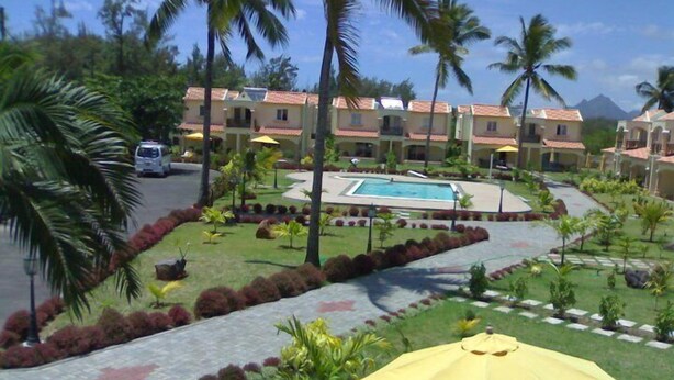 A resort with multiple buildings, a swimming pool, and palm trees. - La Residnce les Badamiers (Trou d'Eau Douce)