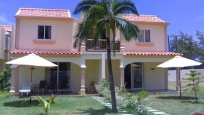 A two-story house with a balcony, a small garden, and two umbrellas. - La Residnce les Badamiers (Trou d'Eau Douce)