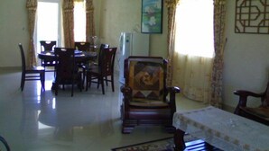 A dining area with a table and chairs, a refrigerator, and a painting on the wall. - La Residnce les Badamiers (Trou d'Eau Douce)