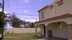 A two-story house with a covered porch and a small garden. - La Residnce les Badamiers (Trou d'Eau Douce)