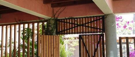 A covered outdoor area with a wooden gate, a stone wall, and potted plants.