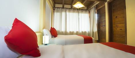 Una habitación de hotel con dos camas, techo de madera, ventana con cortinas y una puerta.