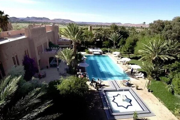 A pool area with palm trees, a star-shaped pool deck, and a view of distant mountains.