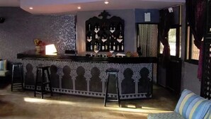 A bar area with a counter, stools, and a decorative wall. - Ouarzazate Le Tichka (Ouarzazate)