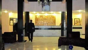 A lobby with a marble reception desk, a chandelier, and a large wall mural. - Ouarzazate Le Tichka (Ouarzazate)
