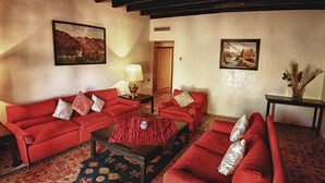 A living room with red sofas, a coffee table, and two paintings on the walls. - Ouarzazate Le Tichka (Ouarzazate)