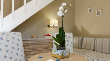 A living room with a sofa, a coffee table with decorative items, a staircase, and a wall-mounted lamp.