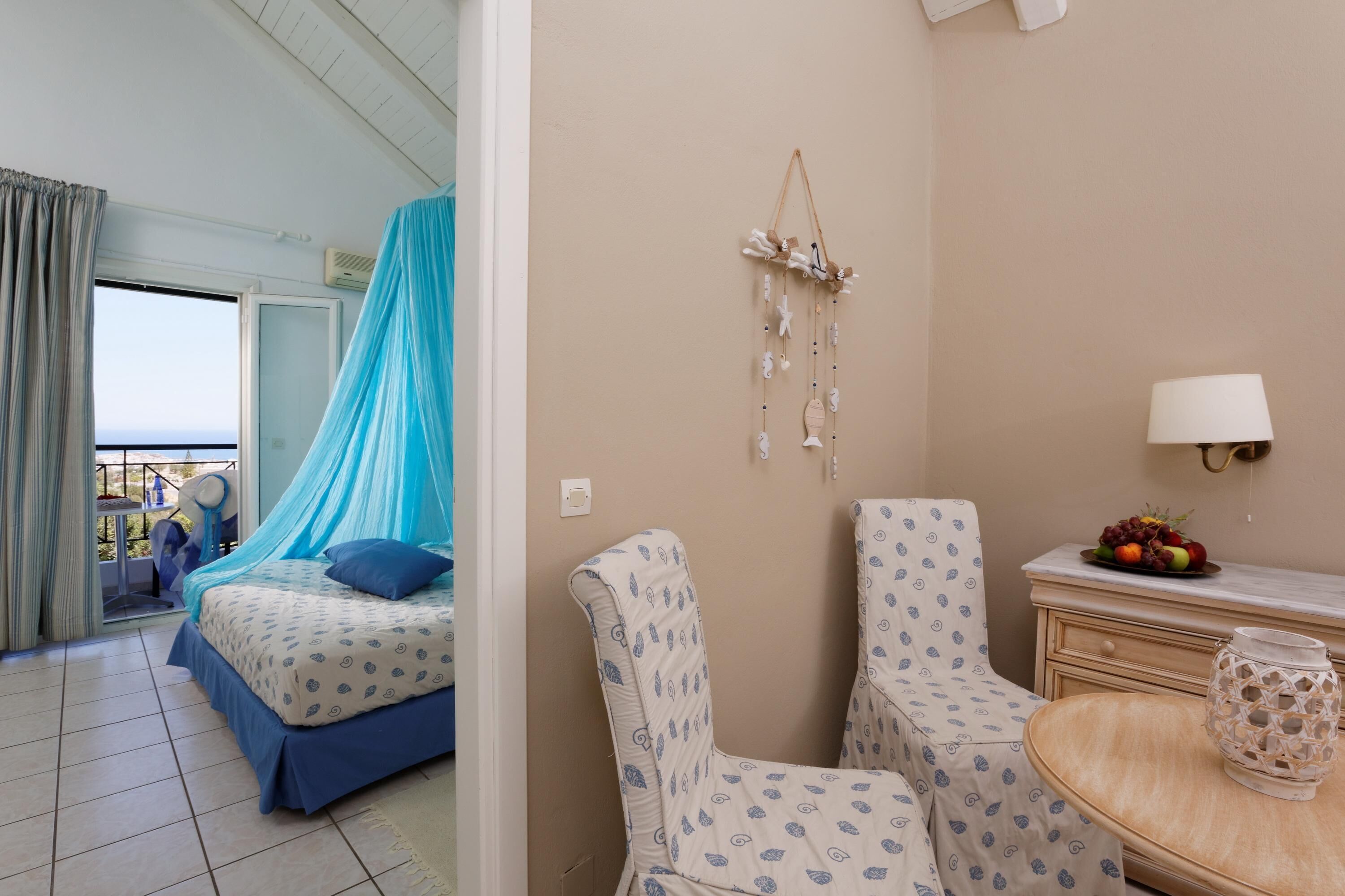 Een hotelkamer met een bed, twee stoelen, een tafeltje met een lamp en een decoratie aan de muur.