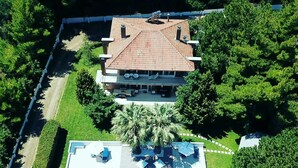 An aerial view of a house with a swimming pool, surrounded by lush greenery and a well-maintained lawn. - Luxurious Villa Anna Maria (Kassandra)