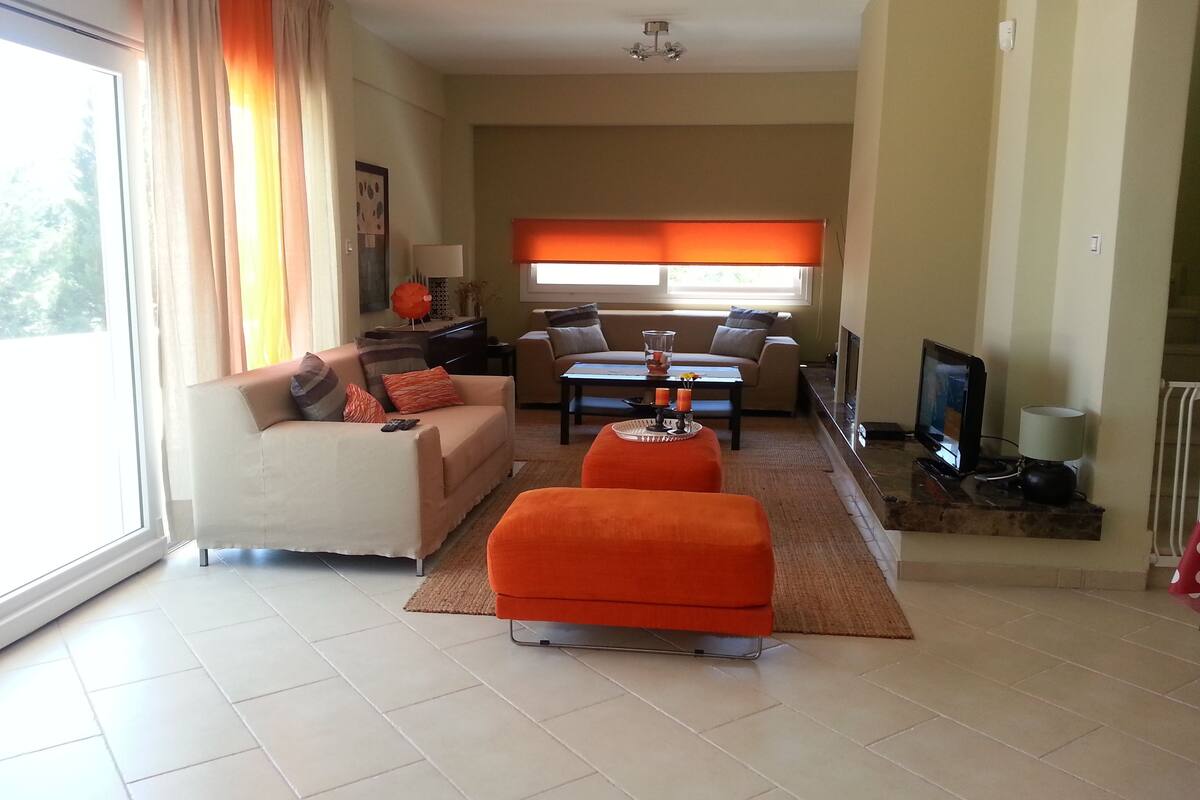 A living room with a sofa, ottoman, coffee table, and a TV.