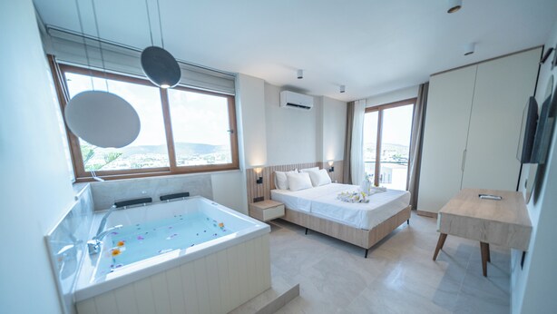 Habitación de hotel moderna con una bañera grande, una cama, un escritorio y vistas a la ciudad.