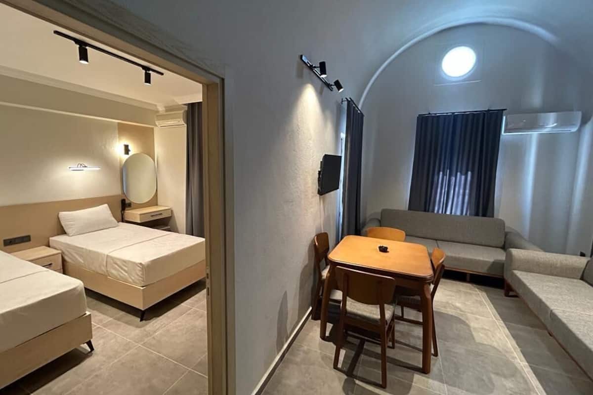 A hotel room with a bed, a desk, a chair, a sofa, and a small table.