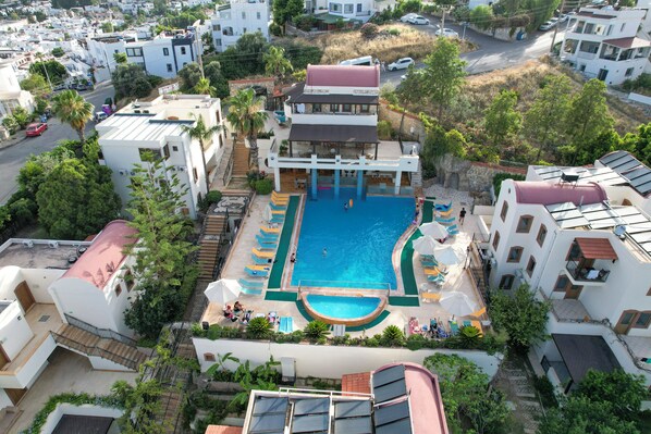 Un quartier résidentiel doté d’une piscine entourée de transats et de parasols.