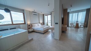 Une chambre d’hôtel moderne dotée d’un grand lit, d’un coin salon avec une table et des chaises, d’une baignoire et offrant une vue sur la ville.