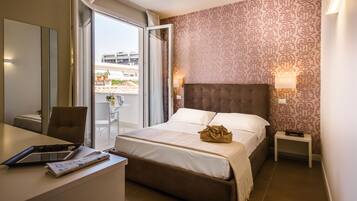 Ein Hotelzimmer mit einem Bett, einem Schreibtisch mit Stuhl, einem Nachttisch und einem Fenster mit Vorhängen.
