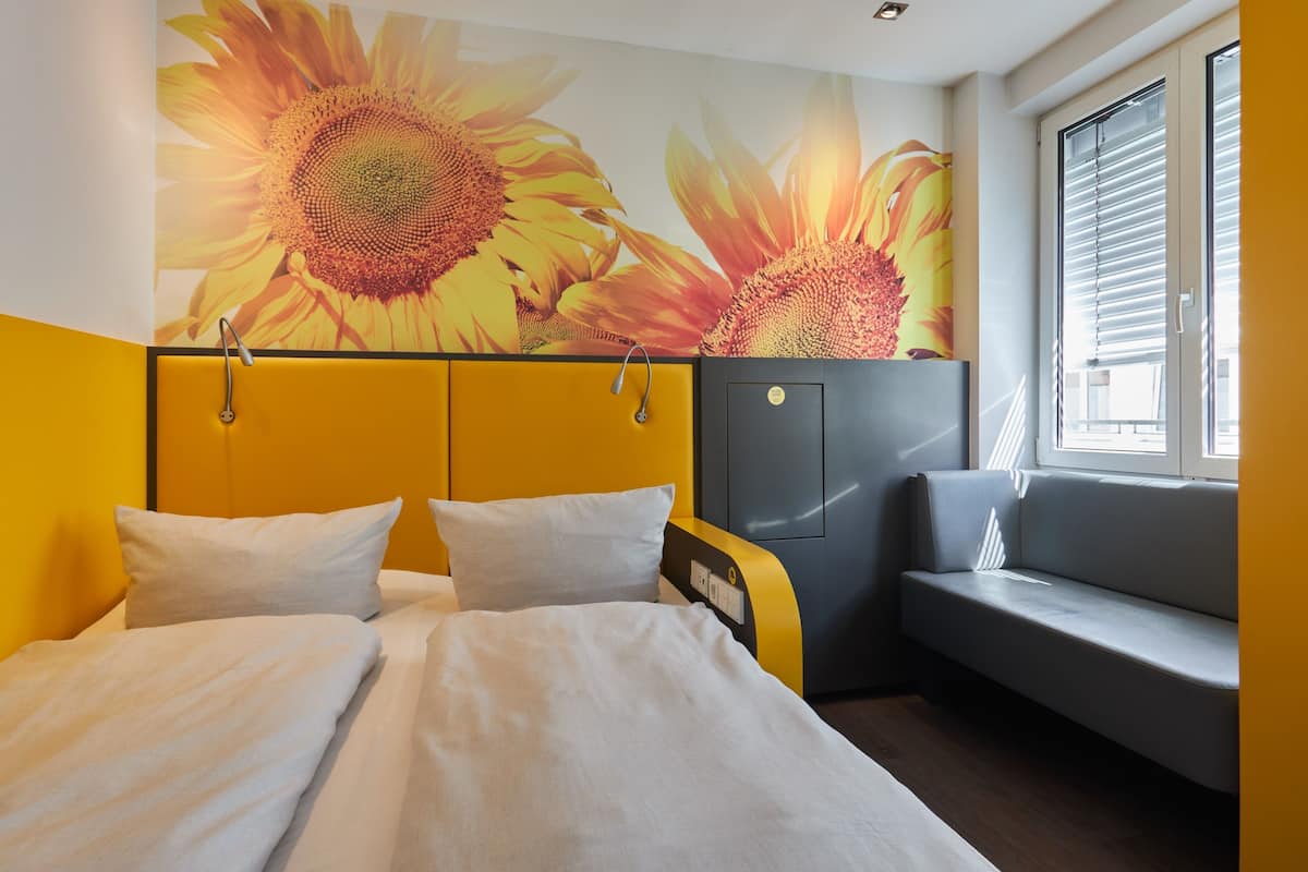 Une chambre d’hôtel avec un lit, un canapé et un mur décoré d’œuvres d’art représentant des tournesols.