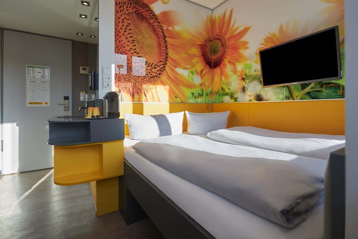 Une chambre d’hôtel avec un lit, un bureau et une grande fresque florale sur le mur.