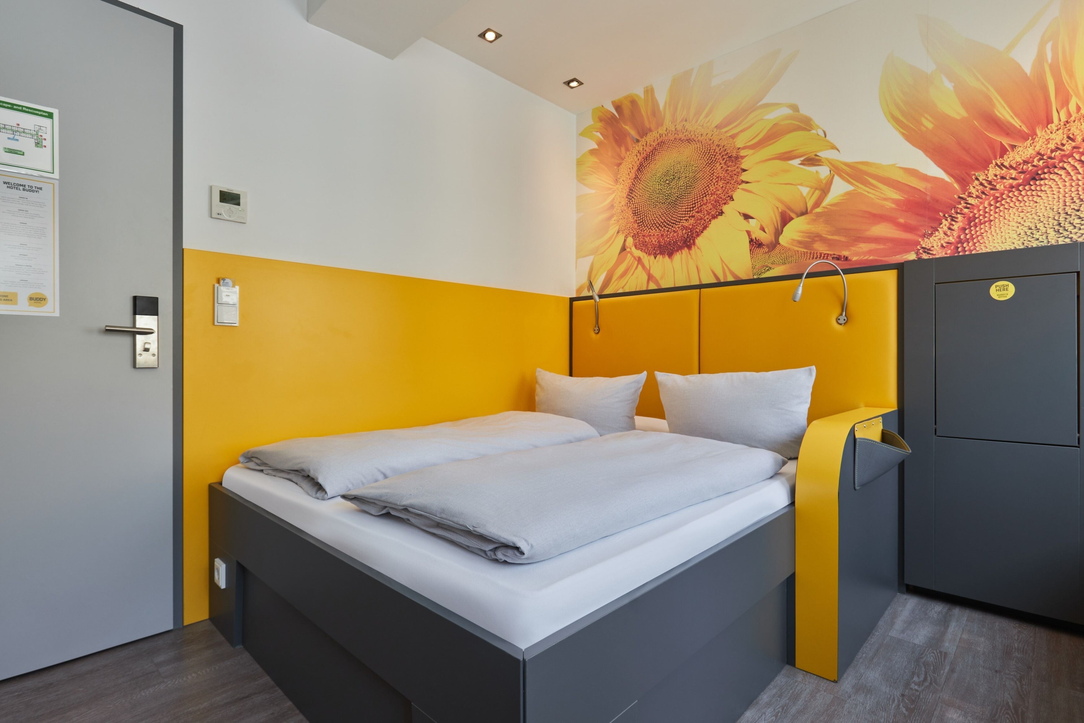 Una habitación de hotel moderna con una cama, un panel de control en la pared y un amplio mural floral.
