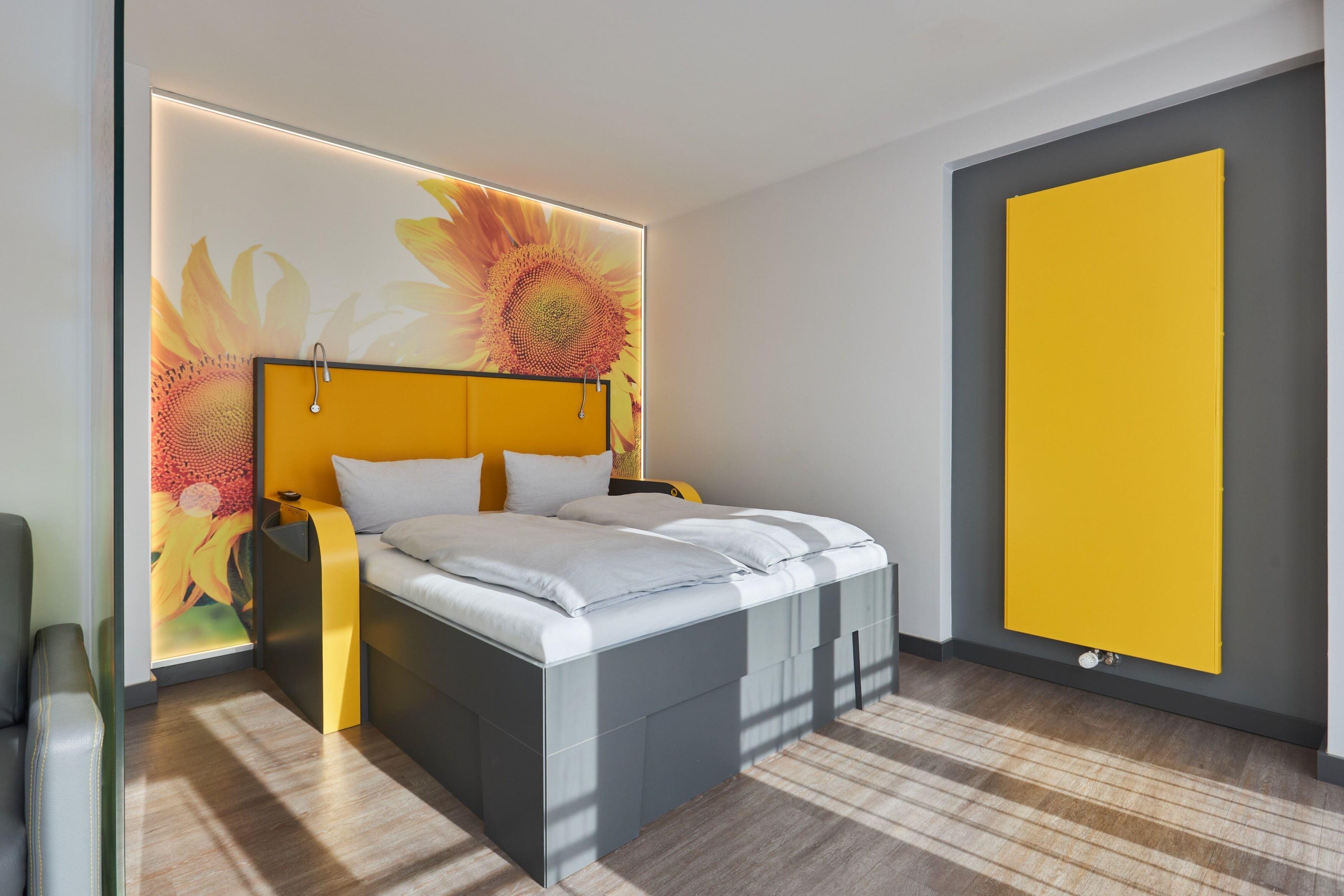 Ein modernes Schlafzimmer mit einem Bett, einem Nachttisch und einem an der Wand montierten Heizkörper.