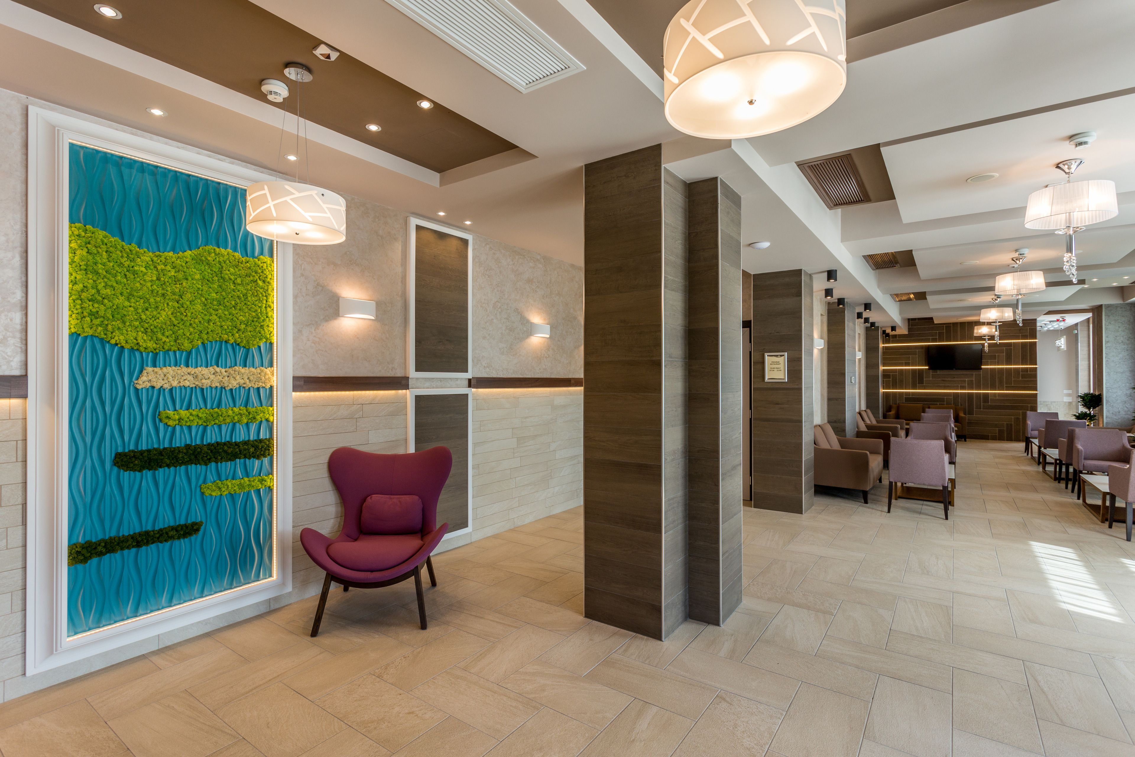 Un lobby moderno con una gran instalación artística en la pared, un mostrador de recepción y un área de estar con múltiples sillas.