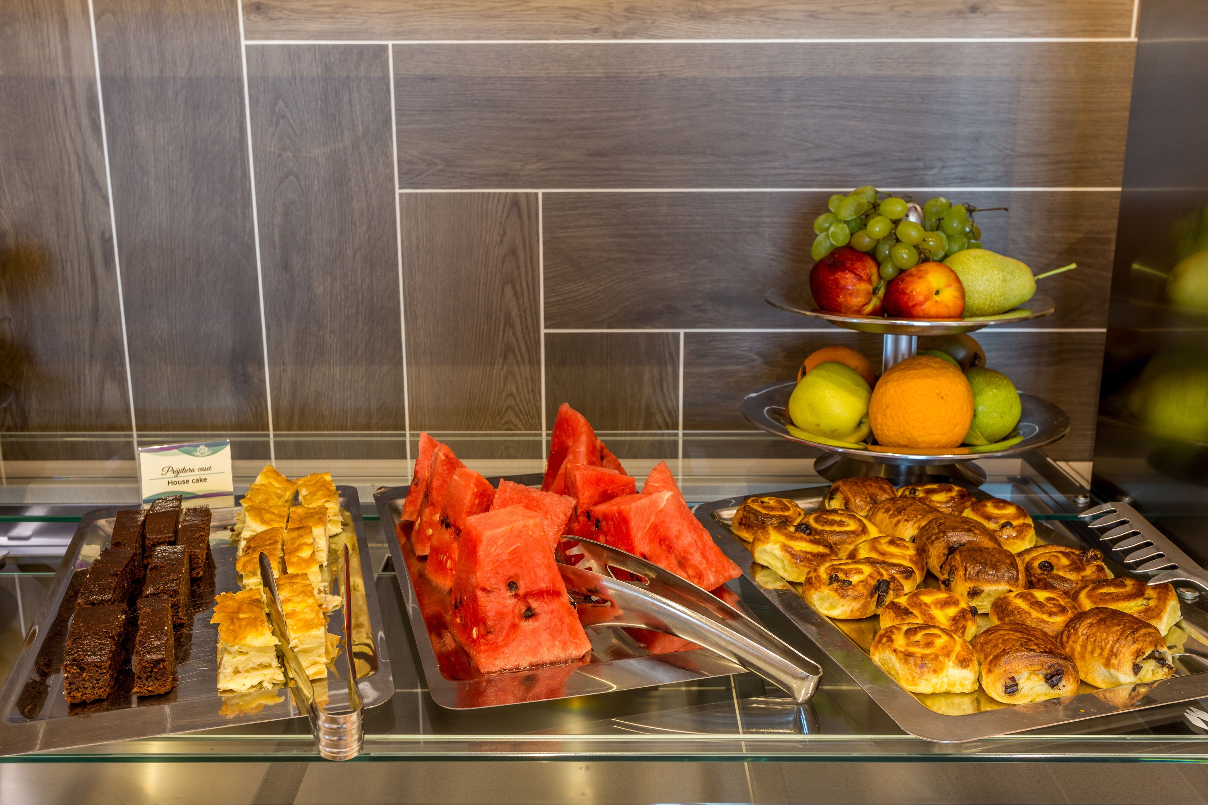 Un bufé con diversos alimentos, incluyendo sandía, pasteles y frutas.
