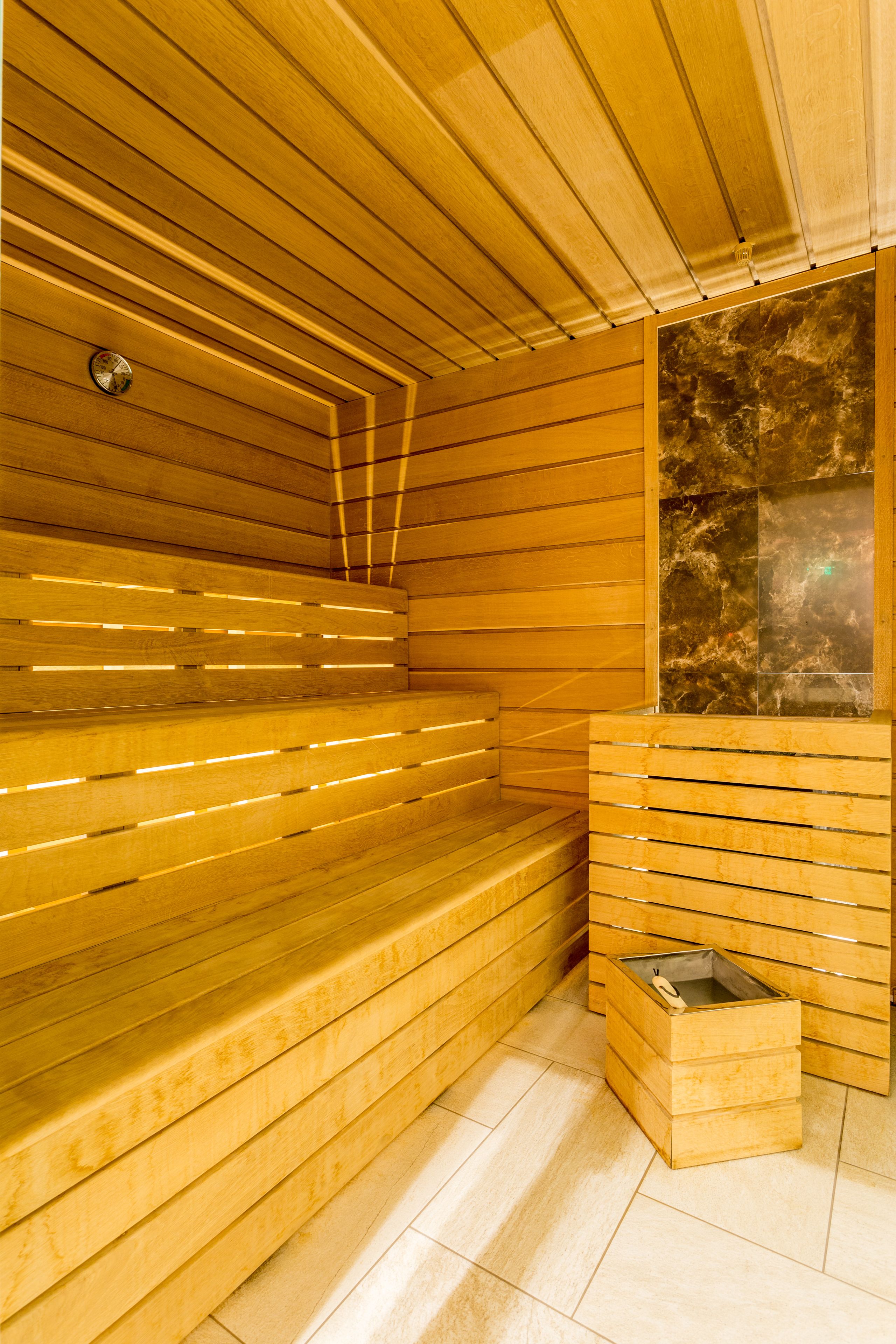 A sauna with wooden benches and a marble wall.