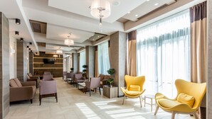 A modern hotel lobby with seating areas, a television, and large windows. - New Splendid Hotel & Spa - Adults Only (Constanta)