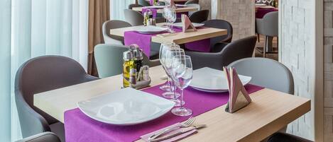 Un restaurante con una larga mesa dispuesta para comer, con manteles morados y sillas modernas.