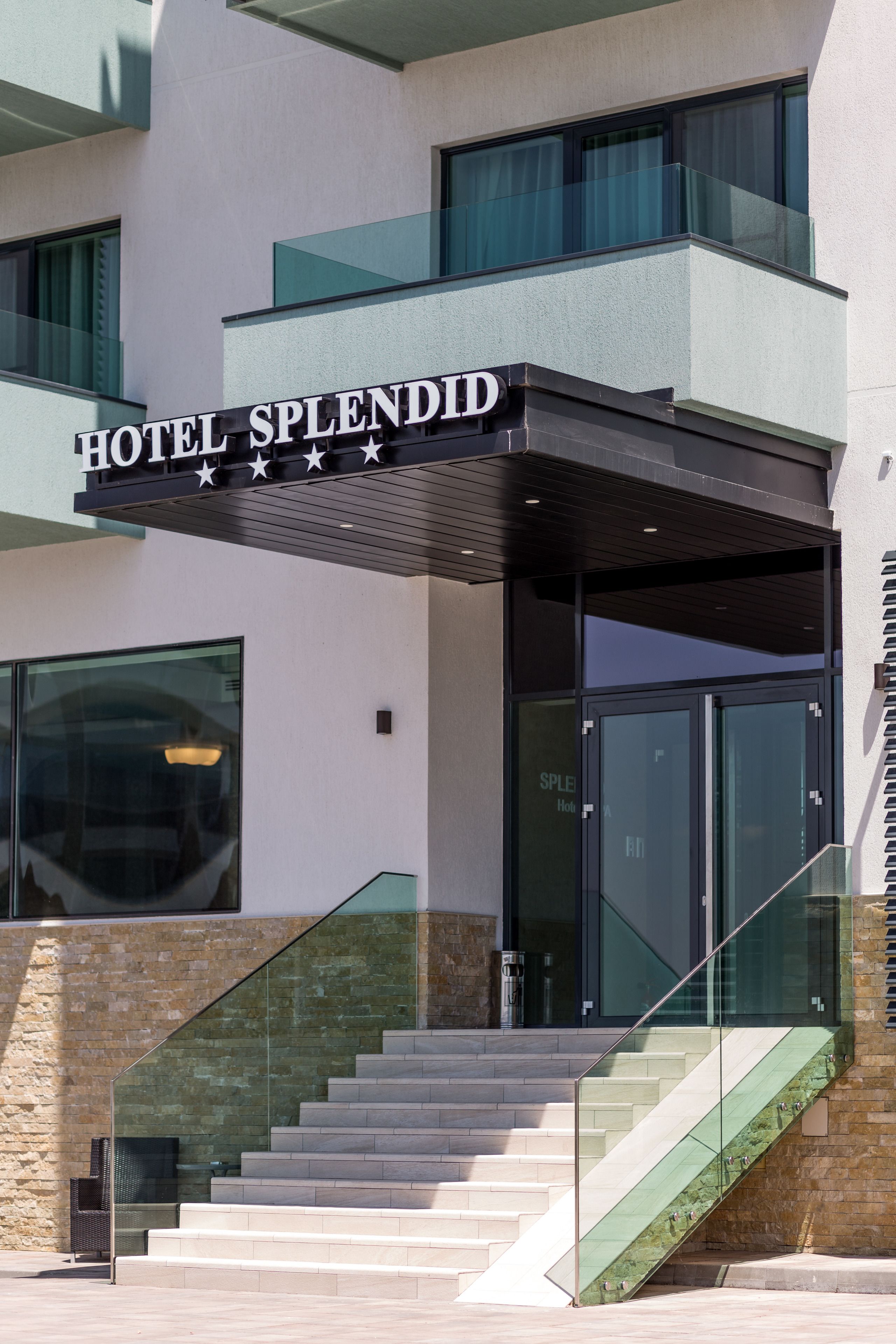 L'ingresso moderno di un hotel con una scalinata in vetro e un cartello che riporta 'HOTEL SPLENDID'.