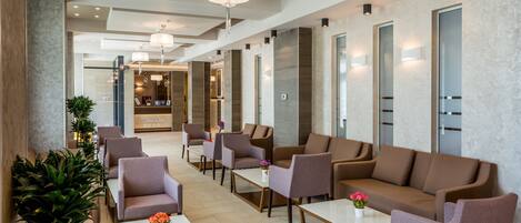 A modern hotel lobby with seating areas, a reception desk, and a spa sign.