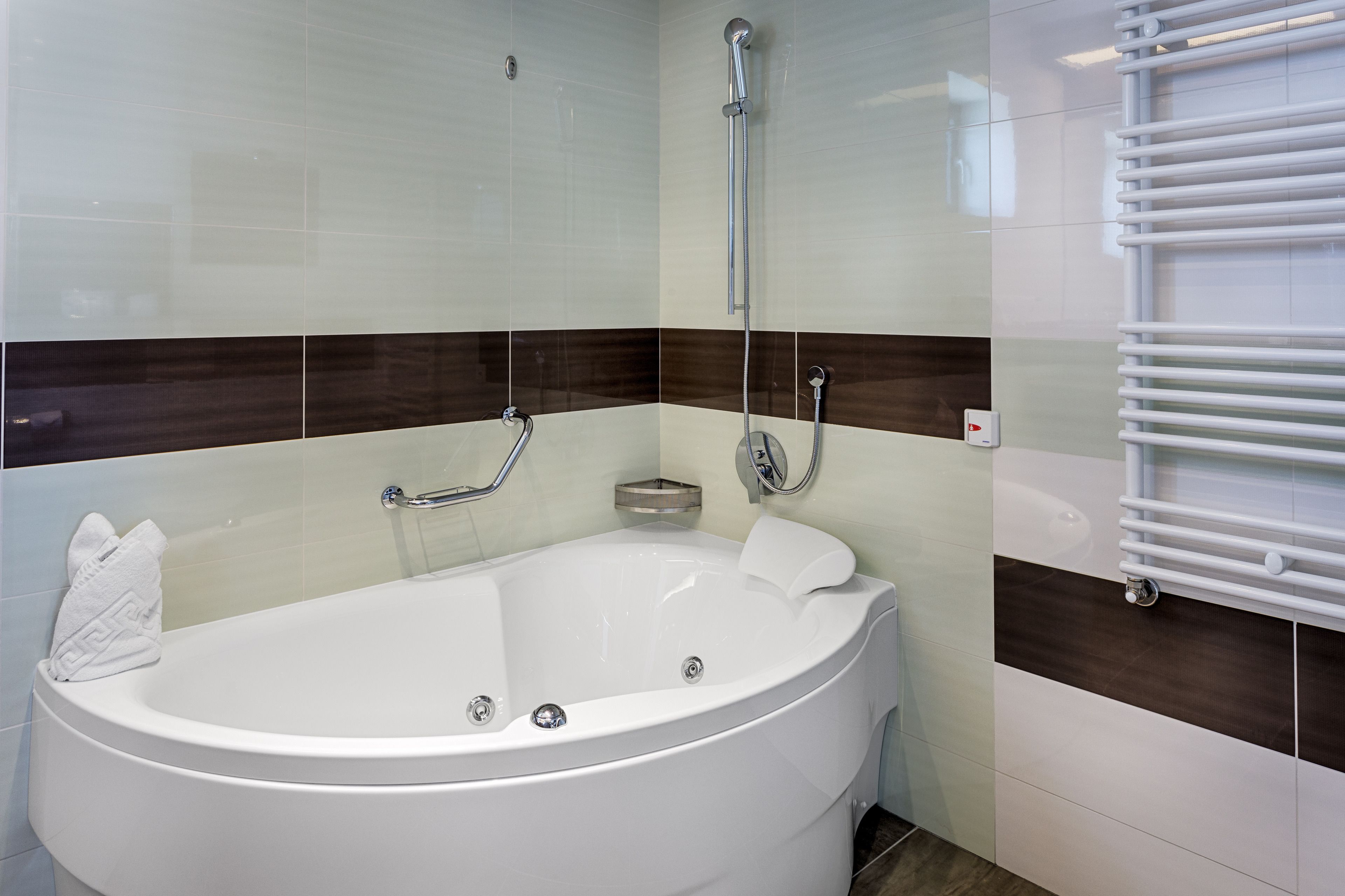 A modern bathroom with a freestanding bathtub, a glass-enclosed shower, and a white towel on the tub.