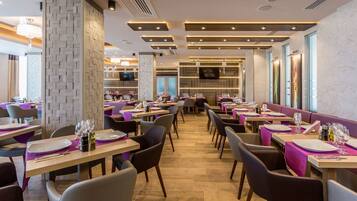 Ein Restaurant mit mehreren Tischen, Stühlen und einem modernen Innendesign.