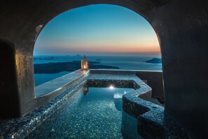 A stone infinity pool with a lantern and a view of the sea at dusk. - Ventus Paradiso Villa (Santorini)