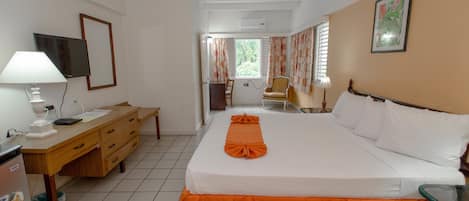 A hotel room with a bed, a desk, a chair, and a window.