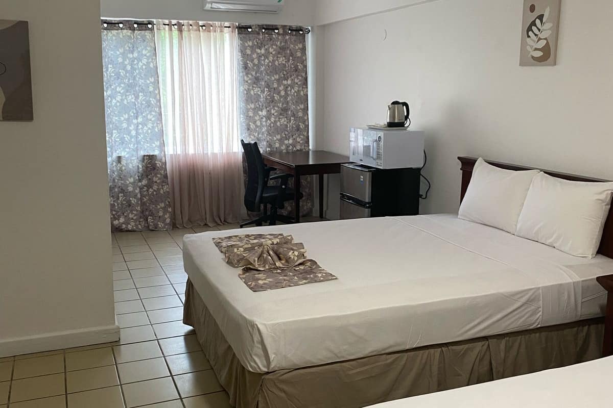 A hotel room with two beds, a desk, a microwave, and a coffee maker.
