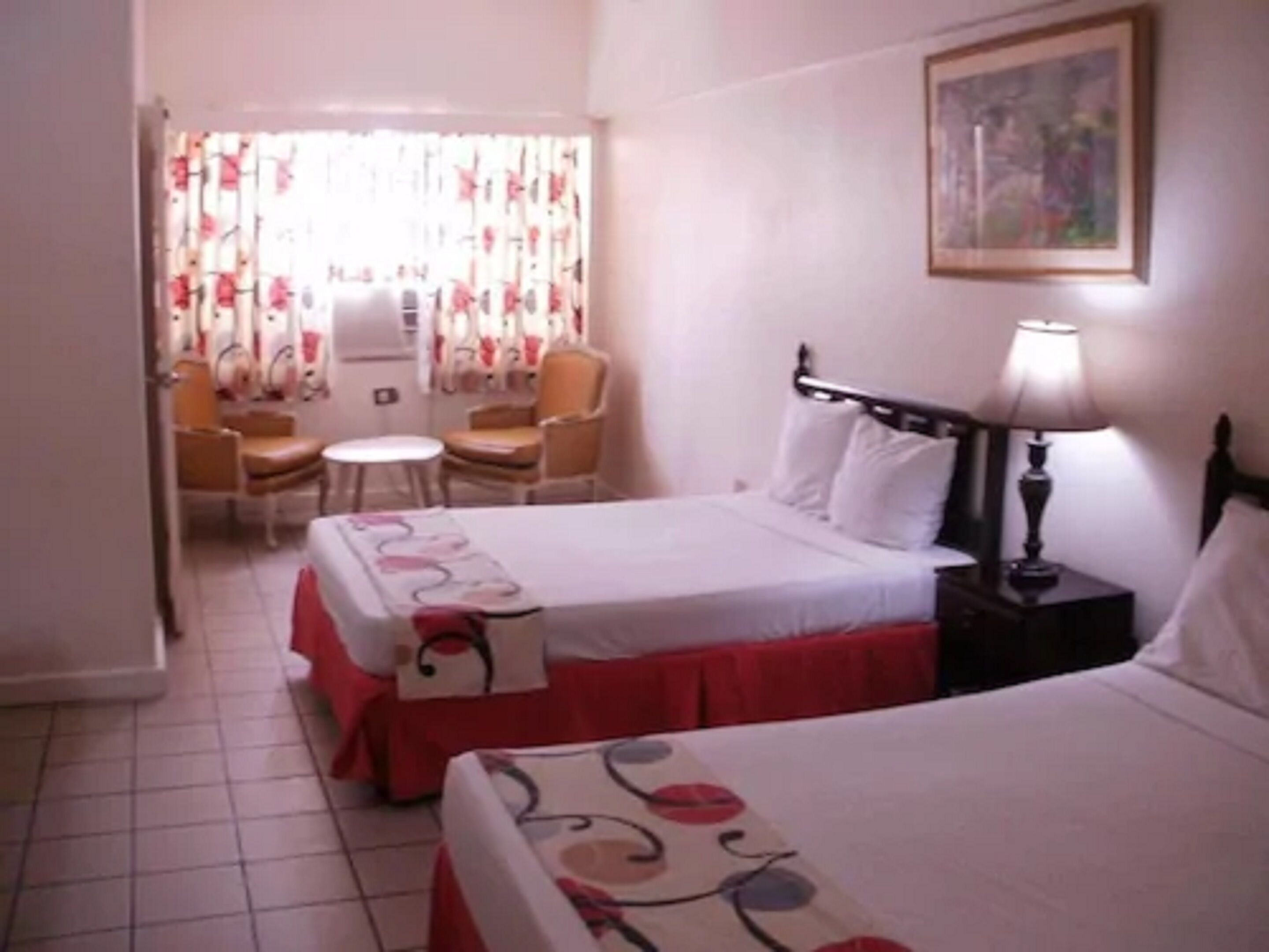 Quarto de hotel com duas camas, uma mesa e uma cadeira.